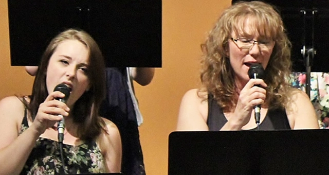Two student performers singing into microphones