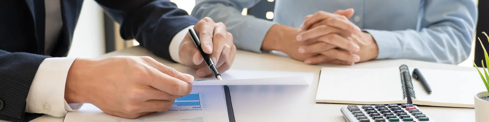 One person showing another person a report on a printed piece of paper above a clipboard.