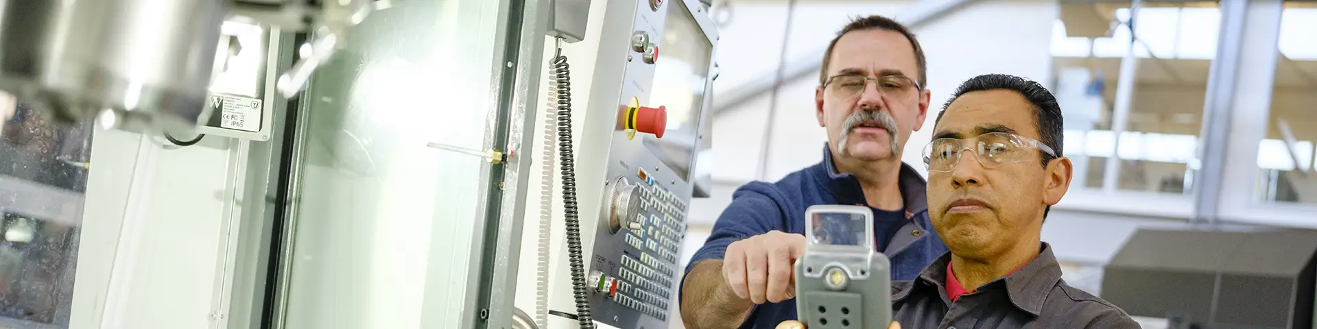 Two people examine manufacturing equipment at CCC's Holden Industrial Technology Center