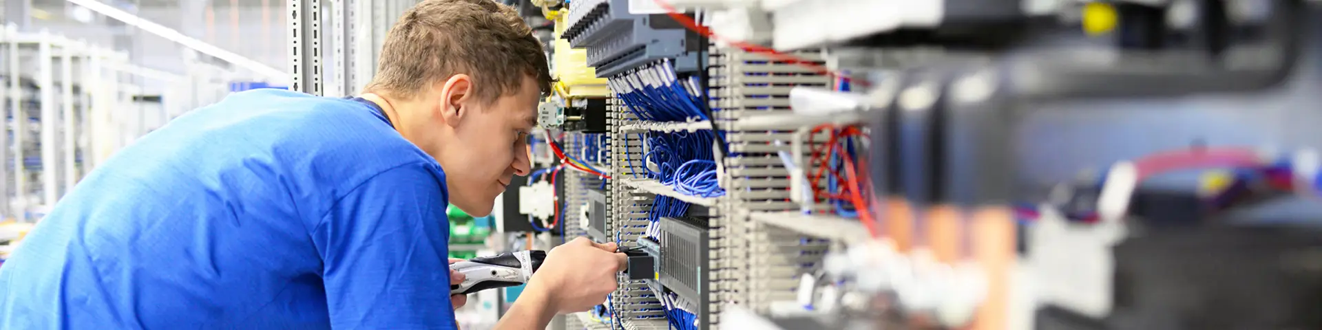 Electronics engineer securing wires to the back of a complex hardware setup.