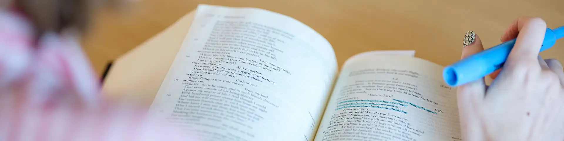 English student reviewing a line they highlighted in blue in their textbook.