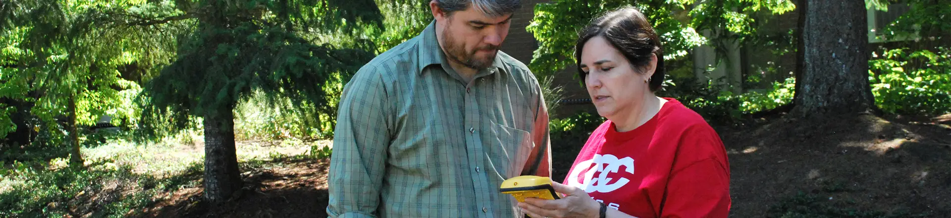 Two people using a GIS mapping tool in a wooded outdoor setting