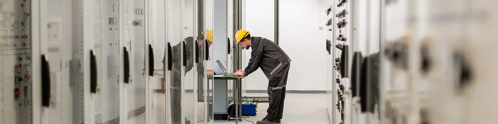 Industrial maintenance worker running hardware diagnostics with a laptop.