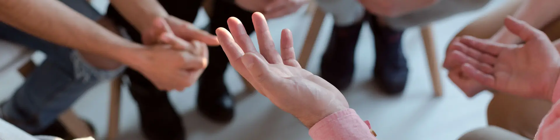 A close up of open hands as people sit in a circle during group counseling.