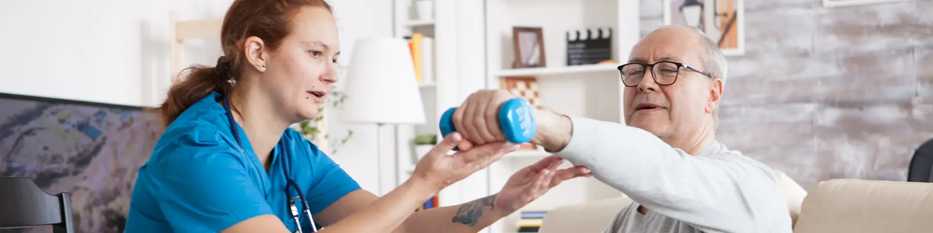 Nurse helping an elder patient do exercise by showing them how to lift light dumbbells.