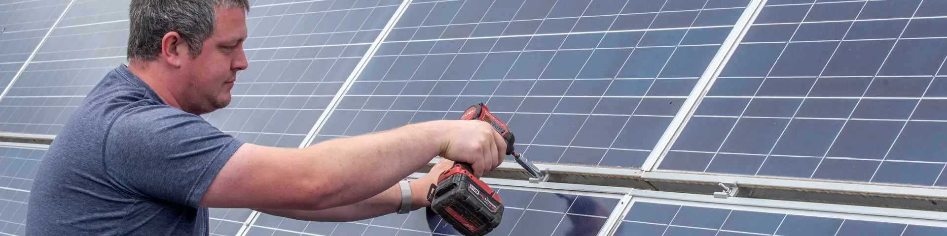 Person using a drill on a solar panel