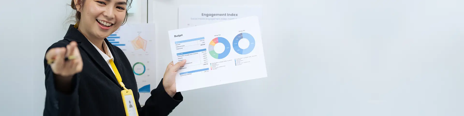 Accounting student holding up a analytics report in front of a whiteboard while fielding presentation questions.
