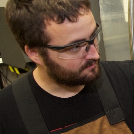 A student in protective eyewear uses CNC technology equipment.