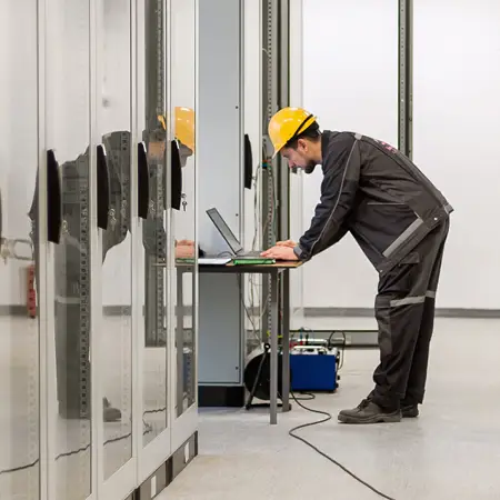 Industrial maintenance worker running hardware diagnostics with a laptop.