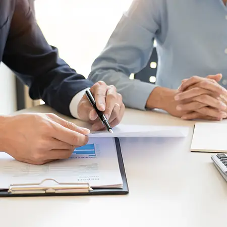 One person showing another person a report on a printed piece of paper above a clipboard.